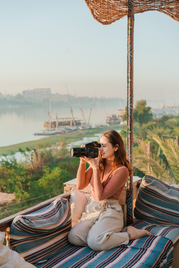 Mujer haciendo una fotografía junto a la vera de un río